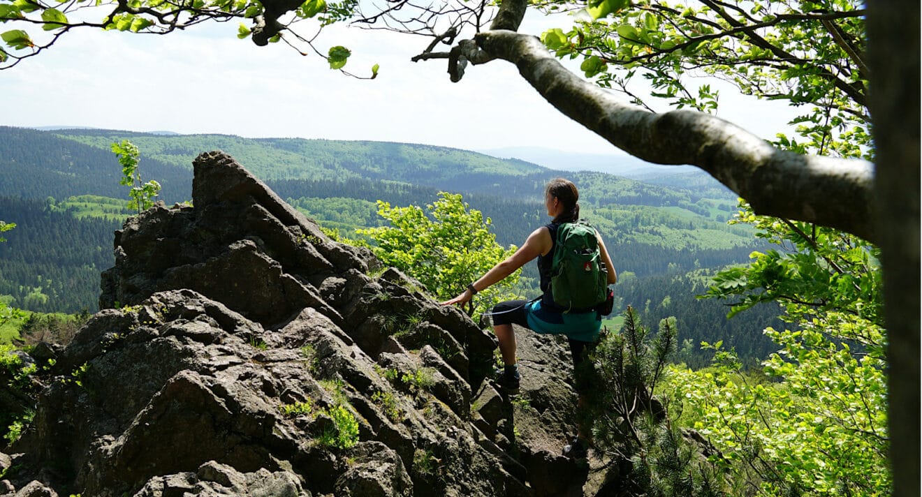 Wanderin steht auf bizarre Klippe und blickt in die weite Landschaft